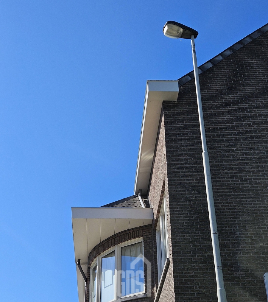 Detail van een nieuwe dakgoot en afvoerbuis tegen een blauwe lucht